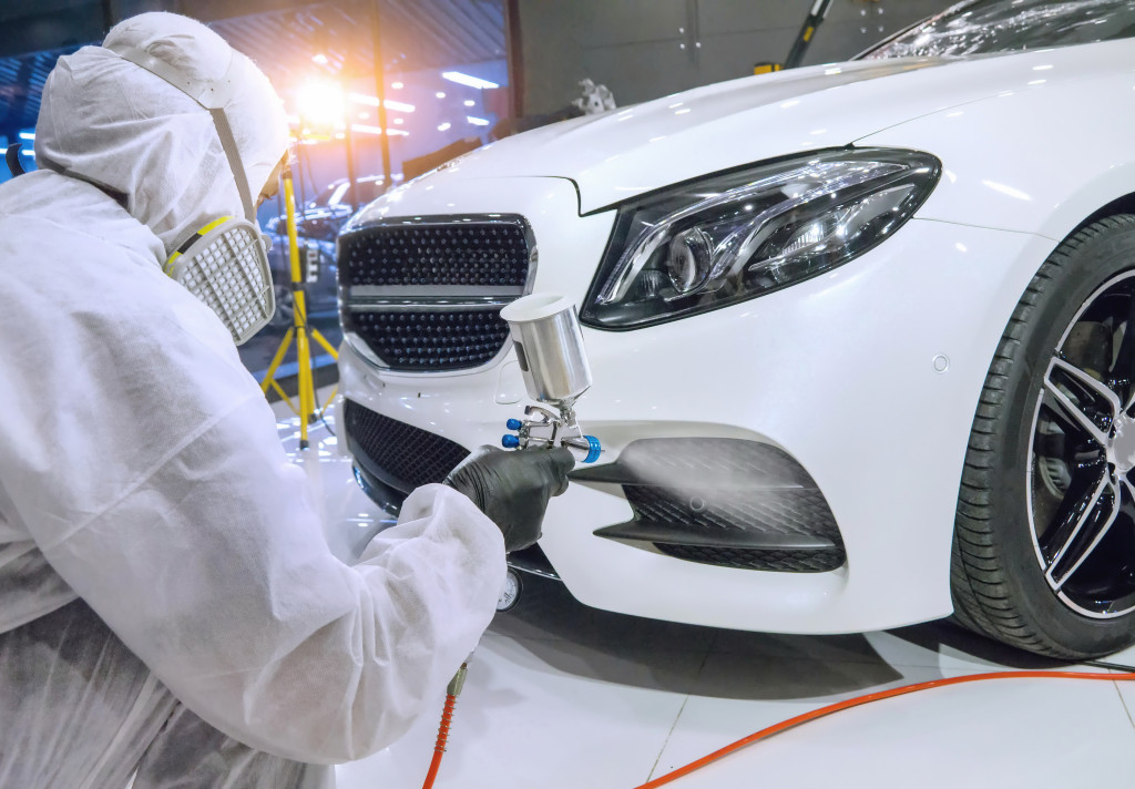 a man using a spray paint to detail a white car